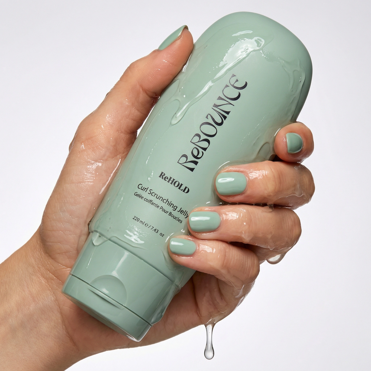 Hand holding a ReHOLD curl scrunching jelly bottle labeled 'Rebounce' with a white background